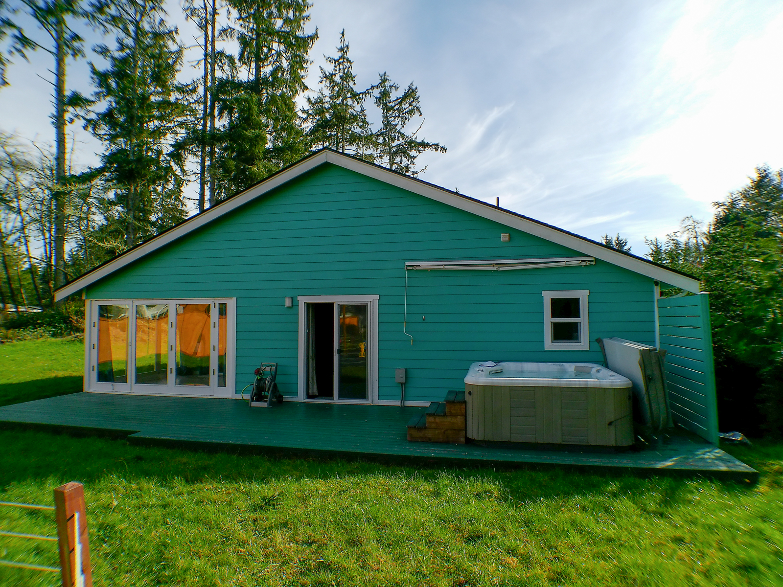The back deck is a wonderful space to unwind, featuring a hot tub covered by a retractable awning and direct access to both the master bedroom and sunroom.